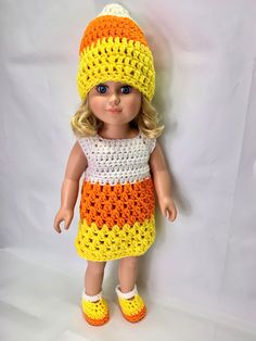 a doll wearing a crocheted dress and hat with yellow, orange, and white stripes