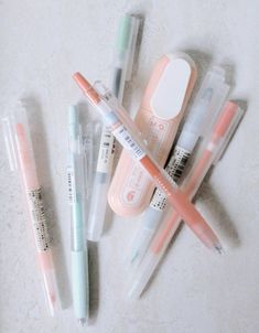 several pens and markers are lined up on the table next to an eraser, toothbrush, and pill bottle