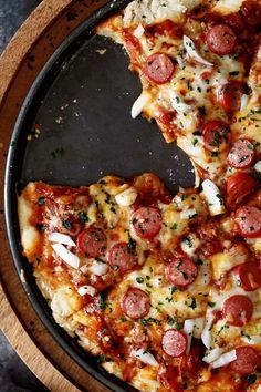 two slices of pepperoni pizza on a wooden platter, with one slice missing