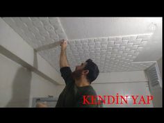 a man is painting the ceiling with white paint and he is pointing at something in the air