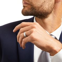 a man wearing a suit and tie with a ring on his left hand, looking off to the side