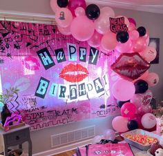 a birthday party with pink and black balloons on the wall, cake table and decorations