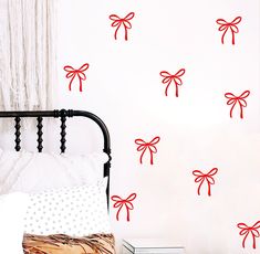 a bed room with a neatly made bed and red bows wall decals on the walls