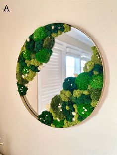 a round mirror with green plants on it