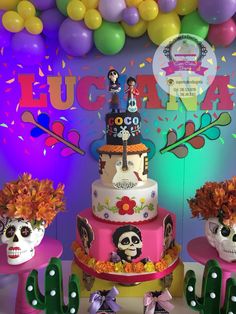 three tiered cake decorated with sugar skulls and flowers in front of balloon garlands