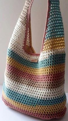 a crocheted bag is sitting on a white table with it's handles down