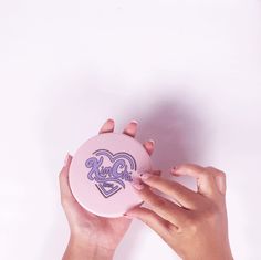 two hands holding a pink frisbee with the word girl on it and a heart