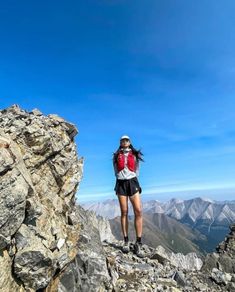 a woman standing on top of a rocky mountain