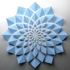 a blue paper flower on a white wall in the shape of an origami