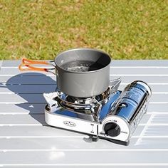 a stove with a pot on top of it sitting on a table next to scissors