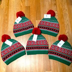 four knitted hats with pom - poms are on the floor