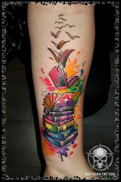 a colorful tattoo on the leg of a woman with books and birds flying over it