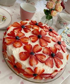 a cake with strawberries and blueberries on it sitting on top of a table