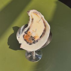 an open oyster on a metal stand with a green table top and shadow from the sun