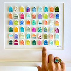 a person's hand is pointing at a colorful art piece