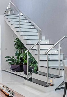 there is a plant on the table next to the stairs in this living room with white walls and flooring