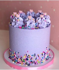 a purple cake with sprinkles and hearts on top