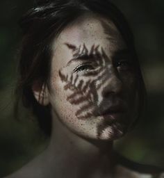 a woman with freckles painted on her face and chest is looking at the camera