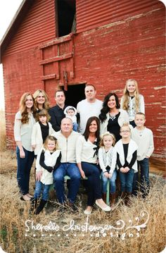 a family poses in front of a red barn