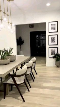 a dining room table with white chairs and plants