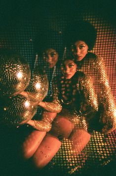 three women sitting on a couch in front of a window with disco balls around them