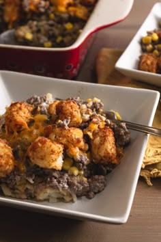 a white plate topped with food next to a casserole filled with tater tots