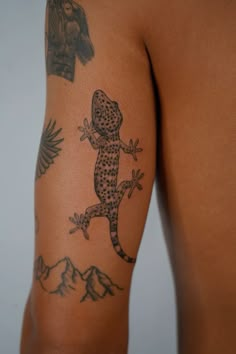 a man with a tattoo on his arm has a gecko tattooed on his back