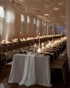 a banquet hall with tables and chairs covered in white draping, lit by candles