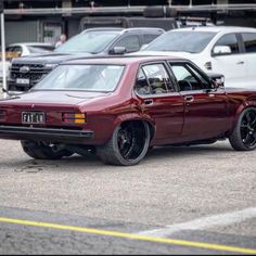 a maroon car parked in a parking lot next to other cars