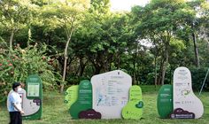 two people are standing in front of some green and white information boards on the grass