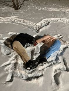 a person laying in the snow with their head on his back and arms around each other