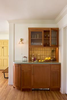 a kitchen area with wooden cabinets and counter tops, wood flooring and white walls