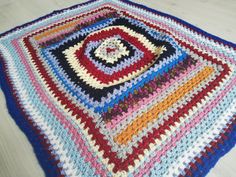 a multicolored crocheted afghan is laying on the floor