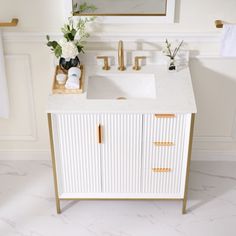 a white sink sitting under a mirror next to a wooden cabinet with drawers and gold faucets