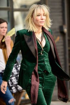 a woman walking down the street with a man in black jacket and hat behind her