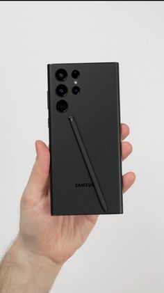 a hand holding up a black samsung note 9 phone in front of a white background