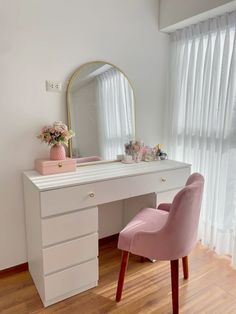 a pink chair sitting in front of a white desk with a mirror on top of it