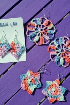 three crocheted earrings are sitting on a purple bench next to a card that says made by me