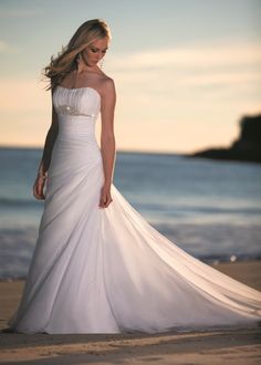 a woman in a white dress standing on the beach