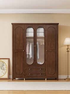 a large wooden cabinet with glass doors in a living room next to a lamp and pictures on the wall