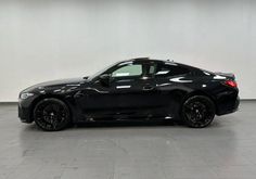 a black sports car is parked in a large room with white walls and tile flooring