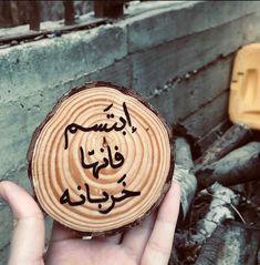 a hand holding a piece of wood with writing on it