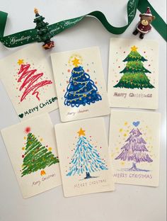 four christmas cards with different designs on them and a green ribbon hanging from the top