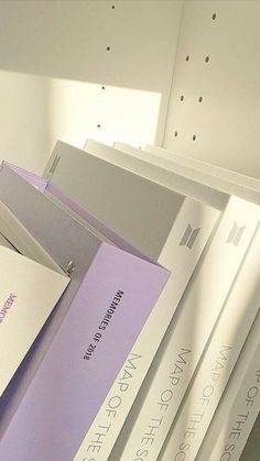 a stack of books sitting on top of each other in front of a white wall