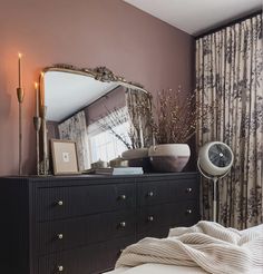 a bed room with a dresser and a mirror on it's wall next to a window