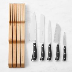 five knives are lined up next to each other on a white counter top with wooden handles