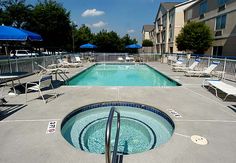 an empty swimming pool surrounded by lounge chairs and umbrellas in a motel or apartment complex