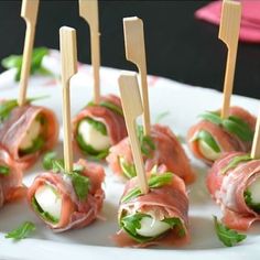 several small appetizers are arranged on a white plate with toothpicks stuck in them