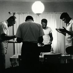 four men are standing in a room looking at something