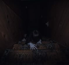 a creepy looking person laying on the floor in a dark room with hands reaching for something